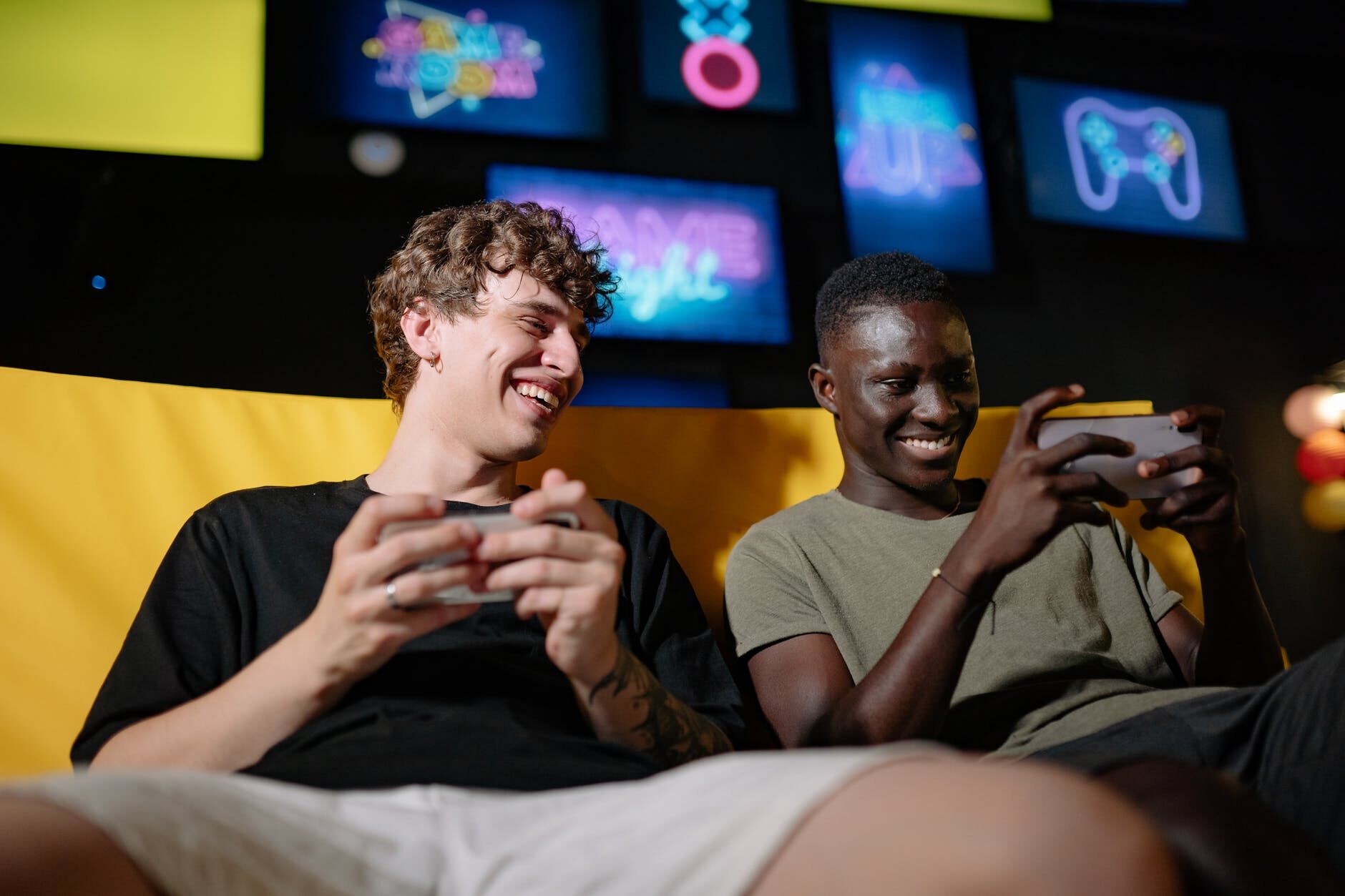 a low angle shot of men sitting on the couch while holding their mobile phones