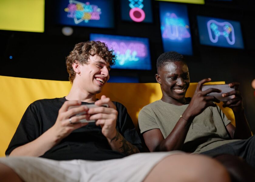 a low angle shot of men sitting on the couch while holding their mobile phones